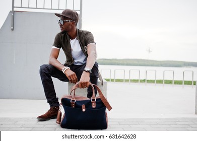 Portrait Of Sitting Stylish African American Man Wear On Sunglasses And Cap Outdoor. Street Fashion Black Man.