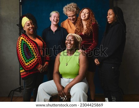 Portrait of six LGBTQIA queer people laughing together for pride month