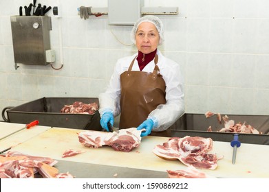 Portrait Of Skilled Female Worker Cutting Raw Meat In Meat Packing Factory
