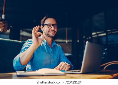 Portrait of skilled male freelancer showing ok sign completing working on project satisfied with salary.successful male IT developer earning money online doing distance job with free schedule