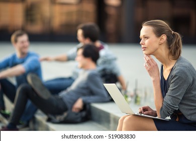 Portrait Of A Sleek Young Woman, Using Laptop Computer, Being Pensive In Urban/city Context (shallow DOF; Color Toned Image)