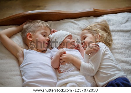 Similar – Baby girl reading book with family in the bed