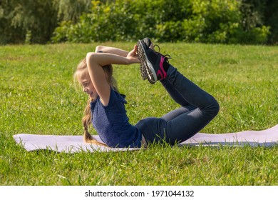 Portrait of slim caucasian teenage girl doing yoga in summer city park. Bow position (Dhanurasana). Healthy lifestyle. Outdoor sport theme. - Powered by Shutterstock