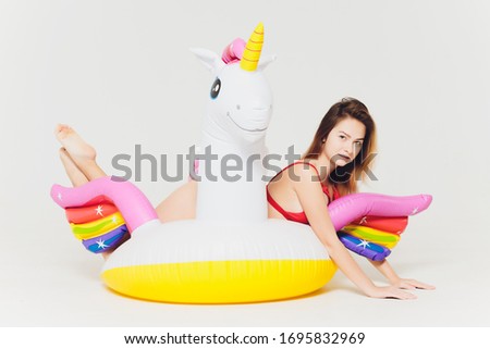 Portrait of slim graceful girl with short blonde hair pink inflatable unicorn.