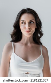 Portrait Of Sly Woman In White Top Isolated On Grey