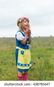 Portrait Of Small Adorable Blond Girl Wearing Traditional Swedish National Folk Costume In Blue And Yellow Colors On Midsummer Celebration 