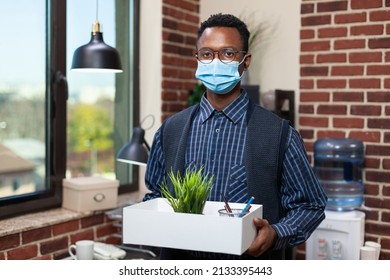 Portrait Of Small Business Employee Leaving Office Holding Tray With Personal Belongings After Company Downsizing Due To Covid Pandemic. Entrepreneur Preparing To Work Remote From Home.