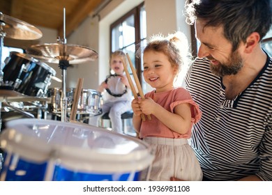 Portrait Of Small Children With Father Indoors At Home, Playing Drums.