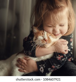 Portrait of a small cute child with a bald head that embraces with tenderness and love a red cat and smiles with happiness - Shutterstock ID 1084607921