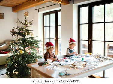 Portrait of small girl and boy indoors at home at Christmas, painting pictures.