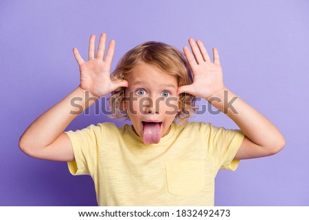 Portrait of small kid boy make funny face show tongue out isolated over violet color background