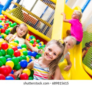 portrait of small smiling girl playing in pool with plastic multicolored balls - Shutterstock ID 689815615