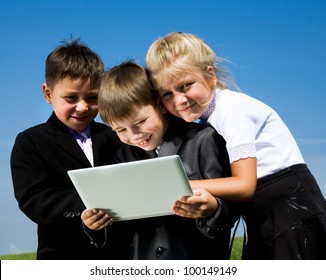 Portrait of small students looking at laptop together