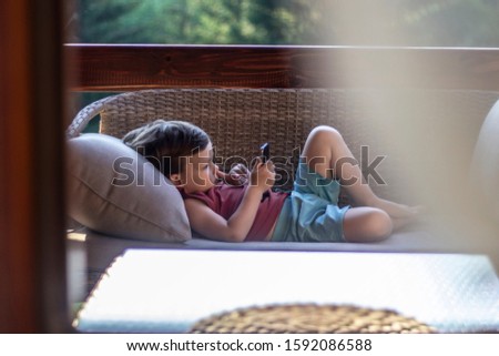 Portrait of small three years old toddler boy addictive on smartphone. Child is using mobile phone. Kid having fun and looking at screen of devices. Technology concept. Copy space.