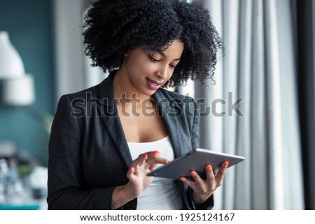 Portrait of smart afro young entrepreneur woman using her digital tablet while standing in the office at home.