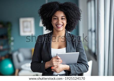 Portrait of smart afro young entrepreneur woman using her digital tablet while standing looking at camera in the office at home.