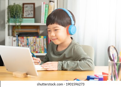 Portrait of a smart asian student boy happily using tablet computer to join virtual classroom for remote learning from home during Covid-19 lockdown, Positive, New normal, Technology, Education - Powered by Shutterstock