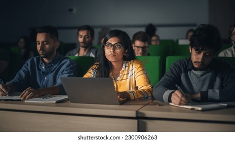 Portrait of a Smart Beautiful Indian Female Student Studying in University with Diverse Multiethnic Classmates. Young Woman Using Laptop Computer and Taking Notes During the Lecture - Powered by Shutterstock