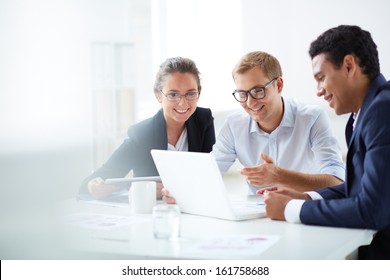 Portrait Of Smart Business Partners Using Laptop At Meeting