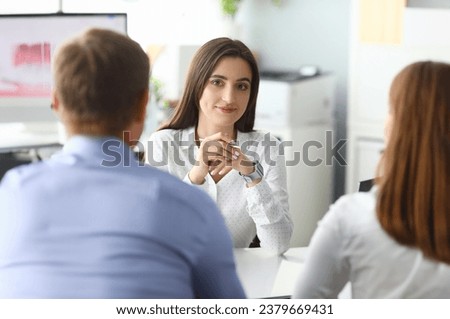 Portrait of smart businesswoman sitting in front of friendly customers and looking at people with concentration and calmness. Office interior. Biz meeting concept