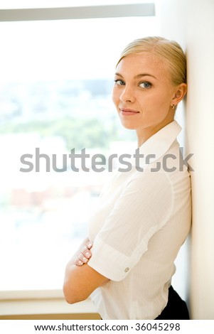 Portrait of smart businesswoman smiling at camera while standing by wall