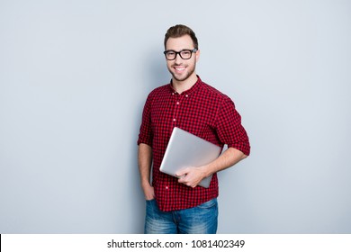 Portrait Of Smart Clever Qualified Promising It-specialist Software Developer Dressed In Red Checkered Casual Shirt, Jeans, Holding Closed Netbook In Hands, Isolated On Gray Background