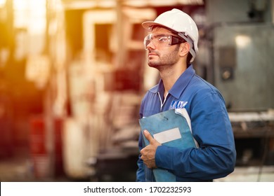 Portrait of smart engineer education machine service manual book happy worker standing proudly in heavy industry background. - Powered by Shutterstock