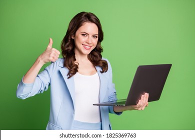 Portrait Of Smart Female Hr Manager Keeping Laptop Smiling Showing Thumb-up Wearing Blue Formal Blazer Isolated On Vivid Green Color Background