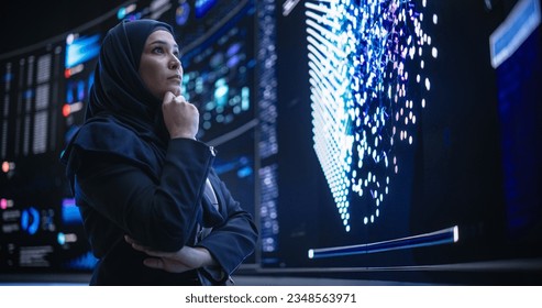 Portrait of a Smart Focused Middle Eastern Software Engineer Analyzing Neural Network Big Data on a Digital Screen. Young Arab Woman in Hijab Working in an Innovative Internet Service Company - Powered by Shutterstock