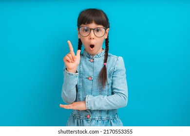 Portrait Of A Smart Girl Child Schoolgirl Jean Jacket Emotional Surprise Finger Up With Glasses Fine Recommend Ad Isolated Over Blue Color Background