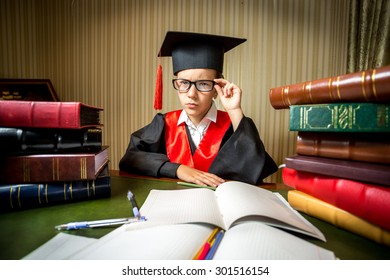 Portrait Of Smart Girl In Graduation Cap And Gown Looking At Camera