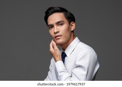 Portrait Of Smart Handsome Asian Man In Corporate Wear Touching Face In Light Gray Isolated Studio Background