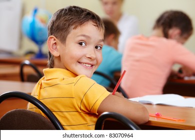 Portrait of smart lad at workplace with classmates on background - Powered by Shutterstock