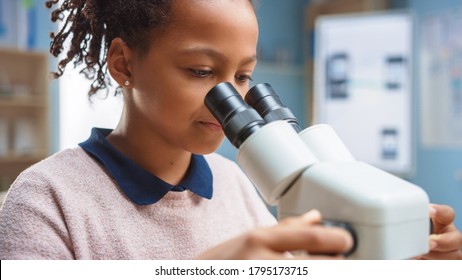 Portrait Of Smart Little Schoolgirl Looking Under The Microscope. In Elementary School Classroom Cute Girl Uses Microscope. STEM (science, Technology, Engineering And Mathematics) Education Program