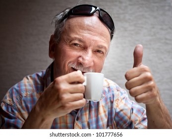 Portrait Of Smart Old Man Drinking Cup Of Coffee And Showing Sign OK With Fingers