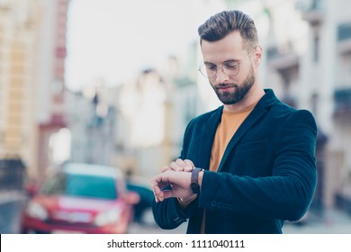 Portrait of smart responsible man with modern hairdo looking at watch on wrist over blurred street background hurry up for meeting. Management employment job concept - Powered by Shutterstock