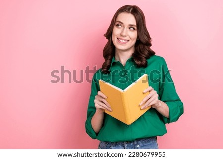 Portrait of smart thoughtful cheerful girl with curly hairstyle wear green shirt look empty space holding book isolated on pink background