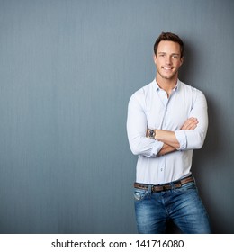 Portrait Of A Smart Young Man Standing With Arms Crossed Against Gray Background