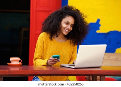 Portrait Of Smart Young Woman With Mobile Phone Working On Laptop At Outdoor Coffee Shop