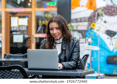 portrait of smart young woman with notebook working on laptop at outdoor coffee shop, work from anywhere concept