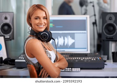 Portrait, smile and a woman music engineer in studio for recording sound or audio as a producer. Computer, software and art with a happy young DJ arms crossed at her desk for professional production - Powered by Shutterstock