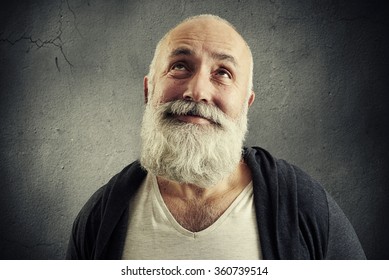 Portrait Of Smiley Bearded Man Looking Up Over Dark Background