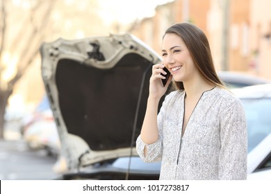Portrait of a smiley driver calling insurance after car breakdown on the street