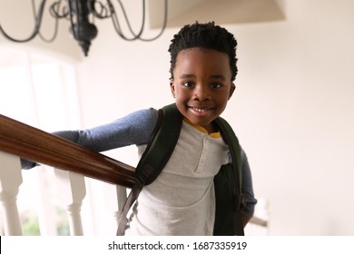 Portrait of smiling African American boy looking to camera with backpack standing on stairs by banister smiling. Social distancing and self isolation in quarantine lockdown for Coronavirus Covid19 - Powered by Shutterstock