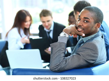 Portrait Of Smiling African American Business Man With Executives Working In Background