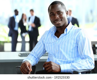 Portrait Of Smiling African American Business Man With Executives Working In Background 