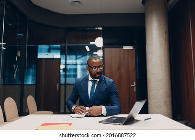Portrait smiling african american businessman in blue suit sit at table for meeting in office with notebook with pen and laptop