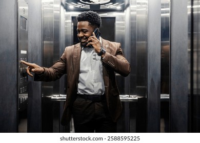 Portrait of smiling african american businessman typing floor number in elevator while having phone conversation. - Powered by Shutterstock - Get 15% off with code: PIKWIZARD15