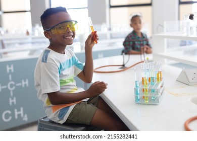 Portrait Of Smiling African American Elementary Schoolboy Showing Test Tube During Chemistry Class. Unaltered, Education, Learning, Laboratory, Stem, Experiment, Protection And School Concept.