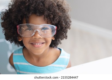 Portrait Of Smiling African American Elementary Schoolboy Wearing Protective Eyewear In Laboratory. Unaltered, Education, Learning, Laboratory, Stem, Experiment, Protection And School Concept.